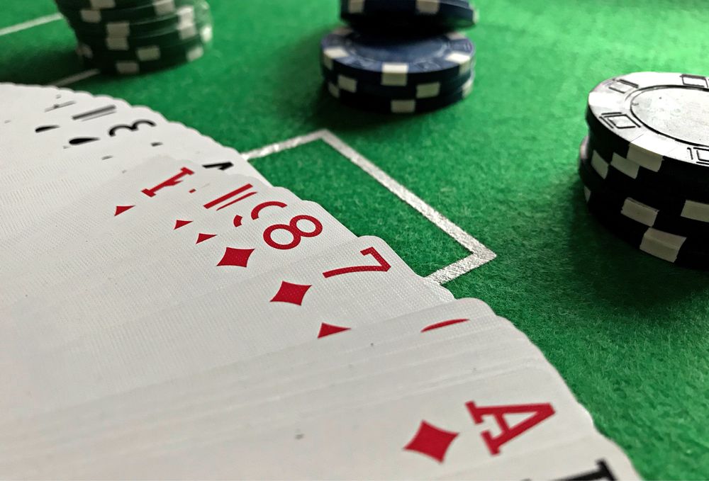 Kartu remi dan chip poker tersusun di atas meja hijau